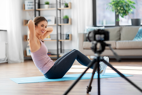 fitness, sport and video blogging concept - happy smiling woman or Vlog with camera streaming online tutorial at home