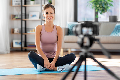 fitness, sport and video blogging concept - woman or Vlog with camera streaming online yoga class at home