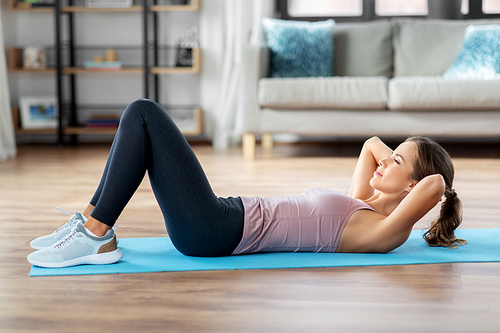 sport, fitness and exercising concept - happy young woman doing sit-ups at home