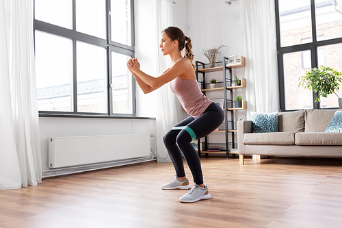 sport, fitness, lifestyle and people concept - woman exercising with resistance band at home