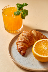 food and eating concept - glass of orange juice with peppermint and croissant on plate for breakfast