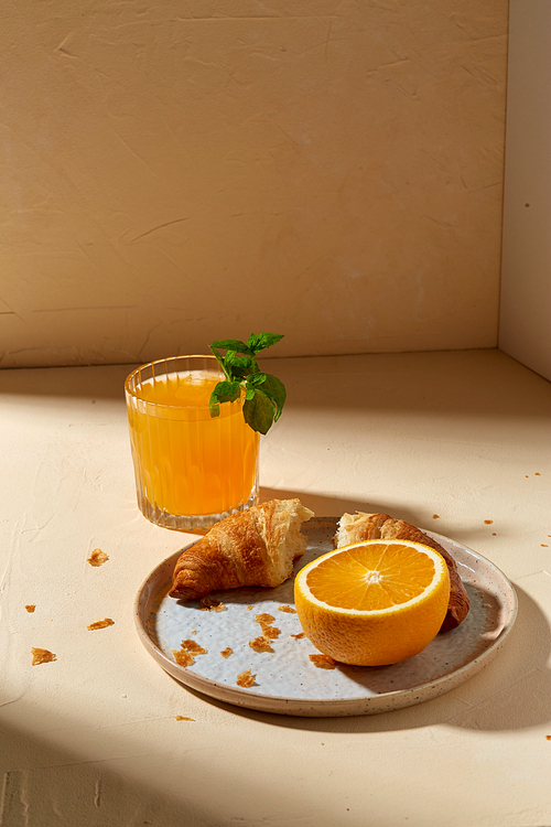 food and eating concept - glass of orange juice with peppermint and croissant on plate for breakfast