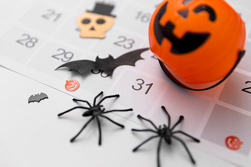 halloween, decorations and holidays concept - close up of jack o lantern, spiders, bat and day in calendar