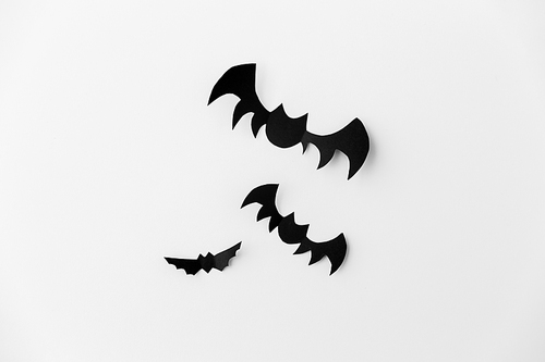 halloween, decoration and scary concept - flock of black paper bats flying over white background