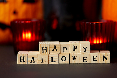 holidays and decorations concept - wooden toy blocks with happy halloween letters on table