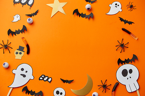 holidays, decoration and party concept - halloween paper decorations and sweets with blank copy space on orange background