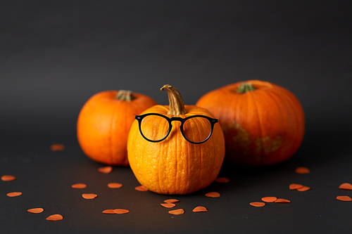halloween and holiday concept - halloween pumpkins with glasses