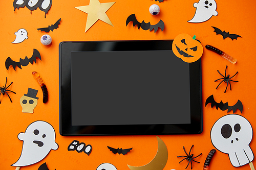 holidays and technology concept - tablet pc computer with halloween party props and decorations