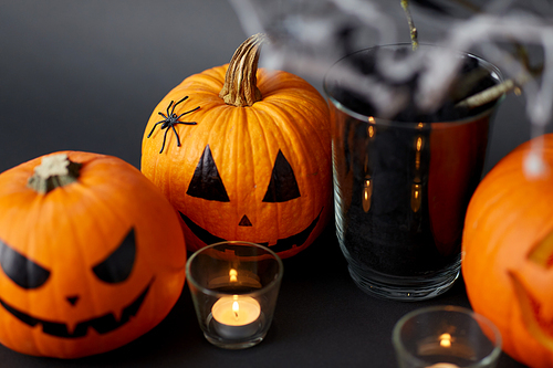 halloween and holiday decorations concept - jack-o-lanterns or carved pumpkins and burning candles