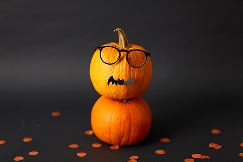halloween and holiday concept - halloween pumpkins with glasses and bat