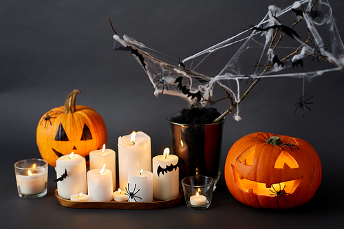 halloween and holiday concept - jack-o-lantern or carved pumpkin, burning candles and spider web decoration