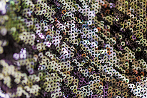 textile, party and texture concept - shimmering fabric with sequins background