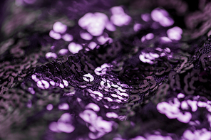 textile, party and texture concept - close up of shimmering violet fabric with sequins background