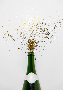 christmas, holidays and celebration concept - champagne bottle and golden glitters on white background