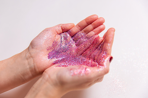 party, decoration and holidays concept - close up of hands with multicolored glitters on white background
