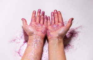 party, decoration and holidays concept - close up of hands with multicolored glitters on white background