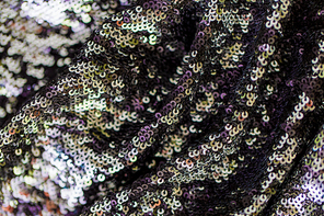 textile, party and texture concept - close up of shimmering fabric with sequins background