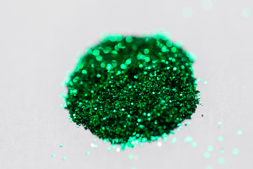 party, decoration and holidays concept - green glitters on white background