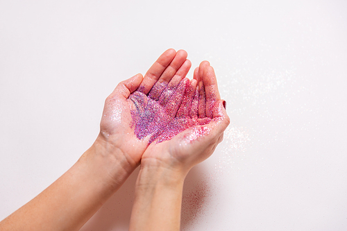 party, decoration and holidays concept - hands with multicolored glitters on white background