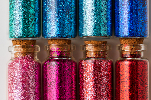 party, decoration and holidays concept - close up of different color glitters in small glass bottles with cork stoppers