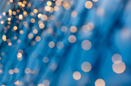 holiday, illumination and decoration concept - bokeh of christmas garland lights over dark blue background