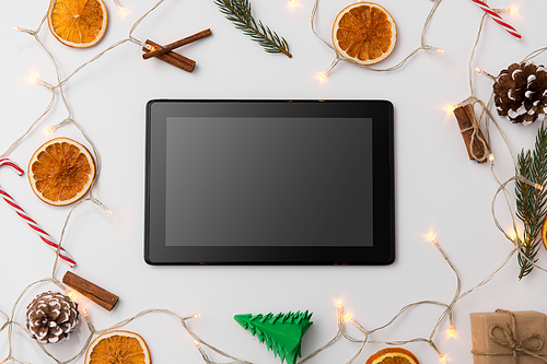 christmas, holidays and technology concept - tablet computer, garland and decorations on white background