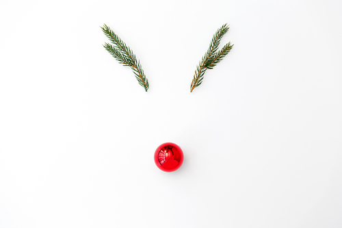 winter holidays, christmas and decorations concept - reindeermade of fir branches and red ball on white background