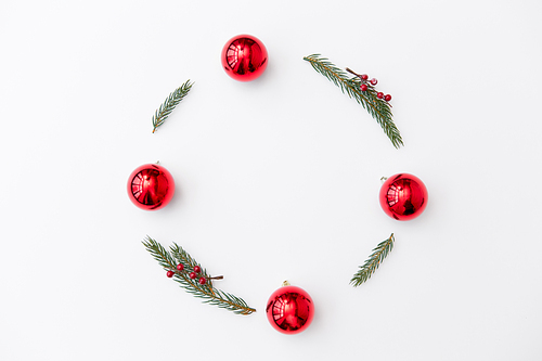 winter holidays, new year and decorations concept - frame of fir branches with red berries and balls on white background