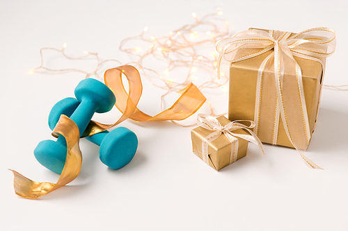 winter holidays, new year and christmas concept - gift boxes wrapped into golden paper and blue dumbbells on white background