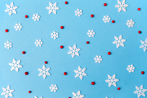 christmas, snow and winter holidays concept - white snowflake decorations and red berries on blue background