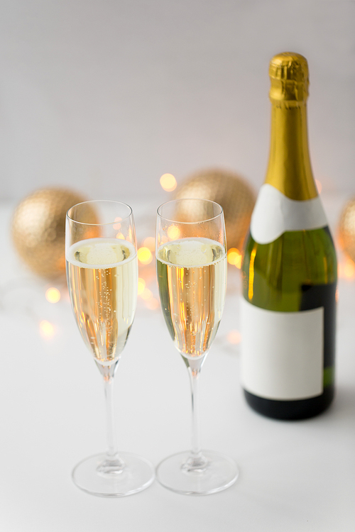 christmas, holidays and celebration concept - two glasses of champagne and bottle