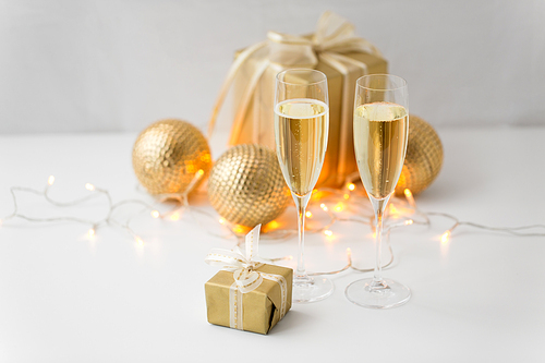 christmas, holidays and celebration concept - two glasses of champagne, gifts and decorations