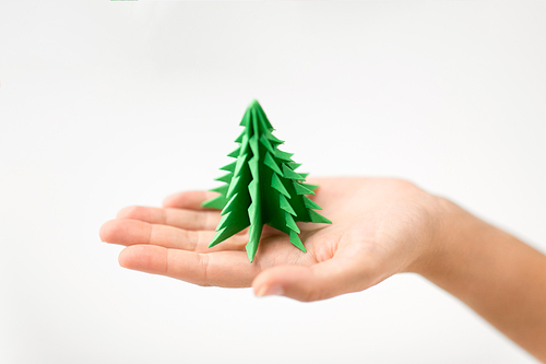 winter holidays, new year and craft concept - hand holding green paper origami christmas tree