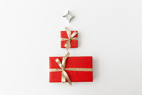 winter holidays, new year and celebration concept - red gift boxes and kitchen mold in shape of star on white background