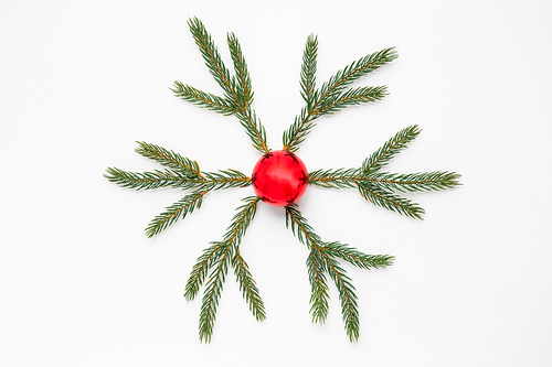 winter holidays, christmas and decorations concept - snowflake shape made of fir branches and red ball on white background