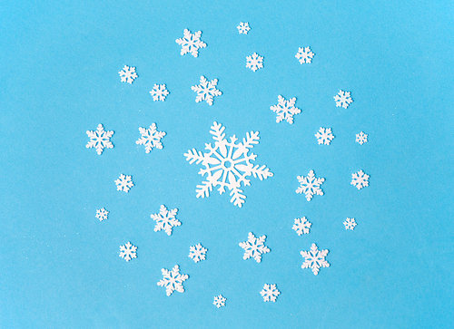 christmas, snow and winter holidays concept - white snowflake decorations on blue background