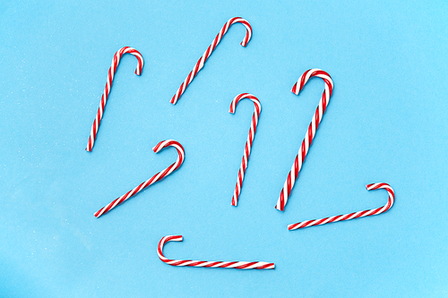 christmas and winter holidays concept - candy cane decorations on blue background
