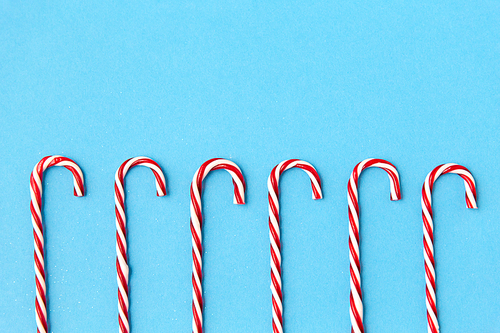 christmas and winter holidays concept - candy cane decorations on blue background