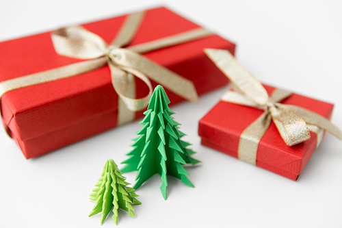 winter holidays, new year and celebration concept - red gift boxes and origami christmas trees on white background