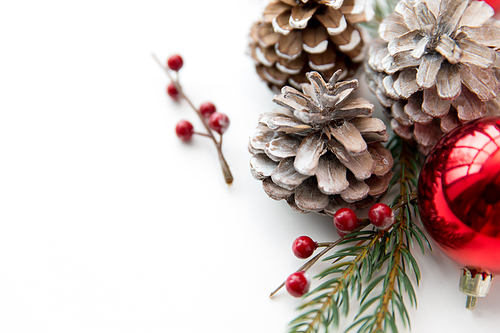 winter holidays, new year and decorations concept - red christmas balls and fir branches with pine cones on white background