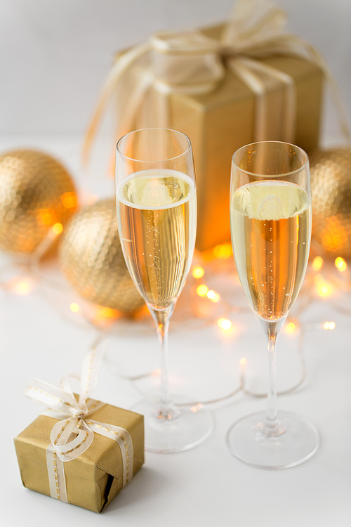 christmas, holidays and celebration concept - two glasses of champagne, gifts and decorations