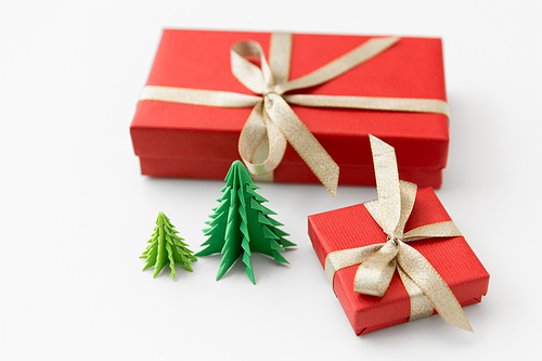 winter holidays, new year and celebration concept - red gift boxes and origami christmas trees on white background