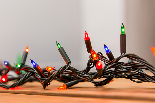 christmas, holidays and illumination concept - electric garland lights on wooden background