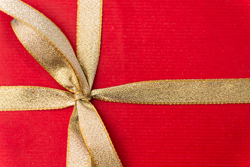 holiday, greeting and surprise concept - close up of christmas red gift box with golden bow
