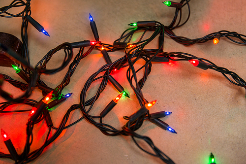 christmas, holidays and illumination concept - electric garland lights on wooden background