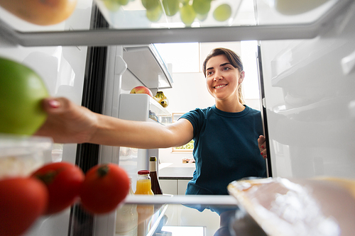 healthy eating, food and diet concept - happy woman taking apple from fridge at home kitchen