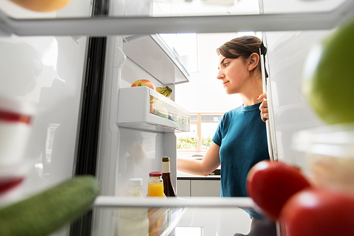 healthy eating, food and diet concept - woman at open fridge at home kitchen