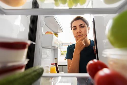 healthy eating, food and diet concept - thoughtful woman at open fridge at home kitchen
