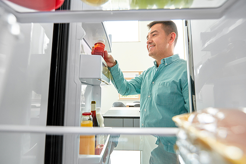 healthy eating, food and diet concept - middle-aged man taking bottle of juice from fridge at home kitchen