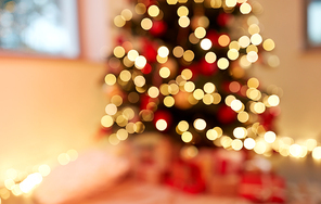 holidays, new year and celebration concept - blurred decorated christmas tree with garland lights at home